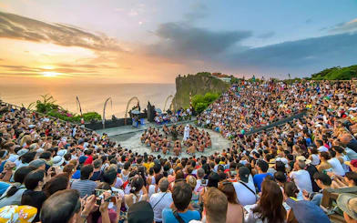 Open-air Kecak dance performance at Uluwatu Temple, Bali, with ocean sunset backdrop.