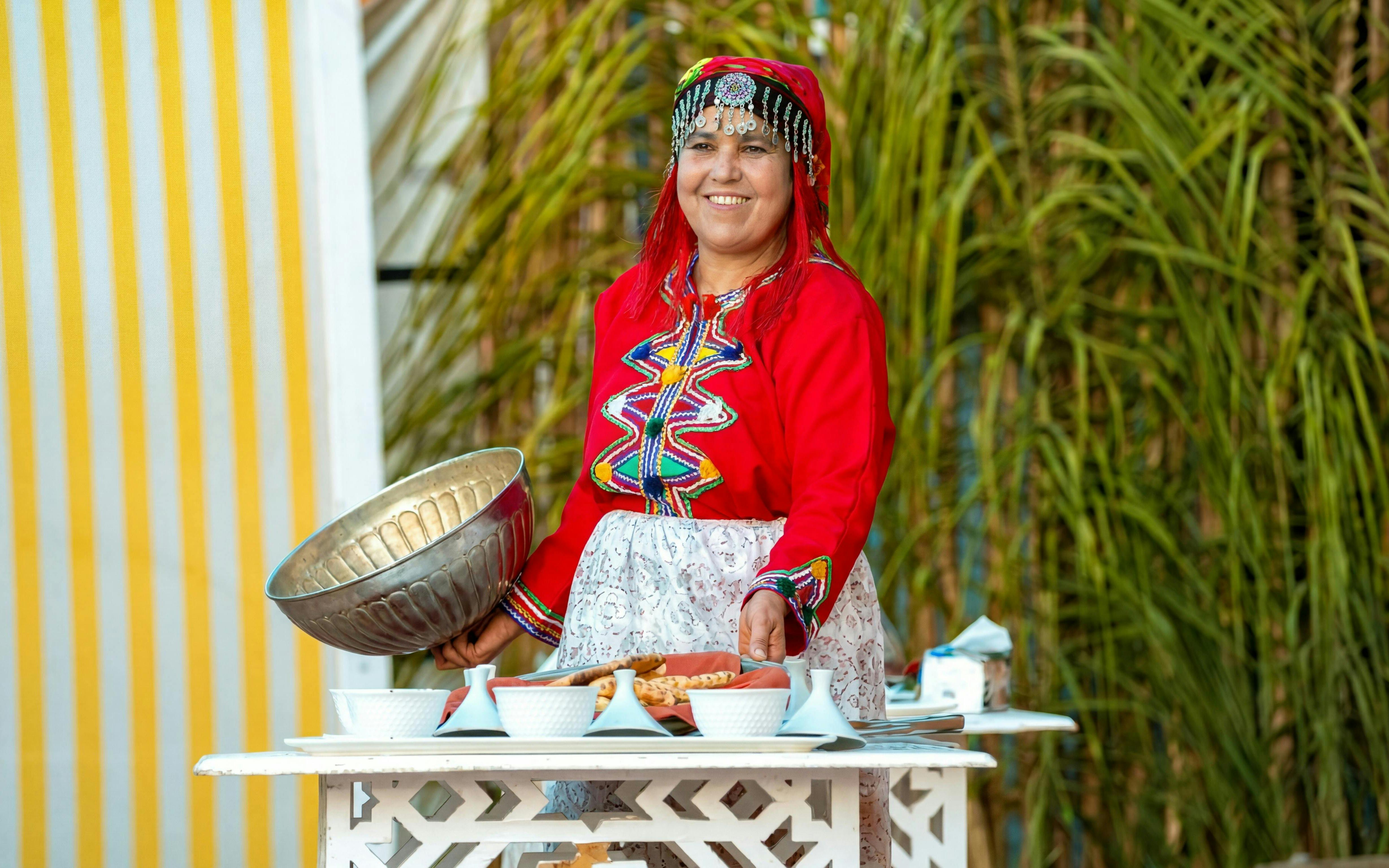 Berber woman in traditional attire preparing dinner at Agadir Fantazia Night Show.