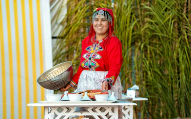 Berber woman in traditional attire preparing dinner at Agadir Fantazia Night Show.
