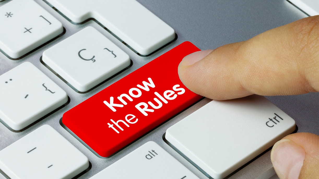 Finger pressing red 'Know the Rules' key on keyboard