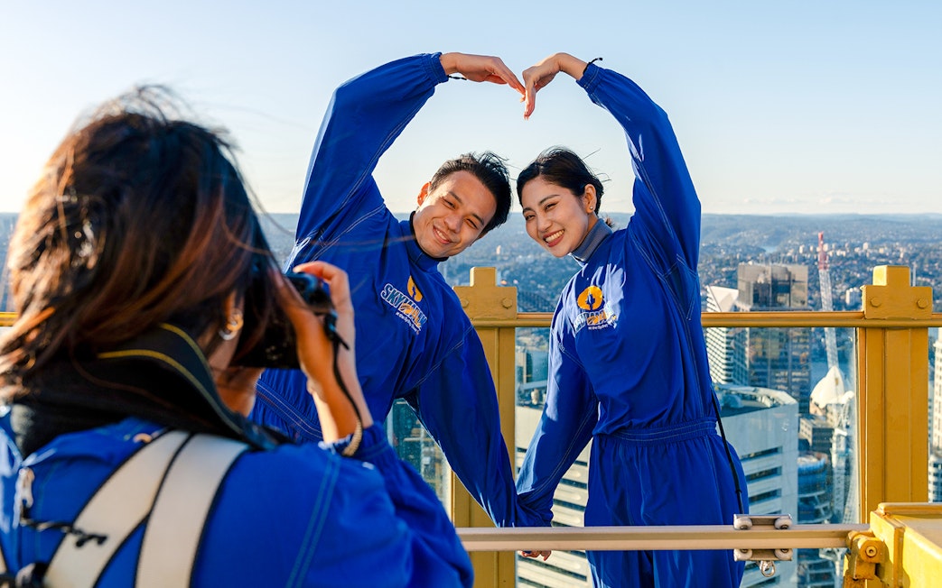 Couple posing on Sydney Tower Eye Skywalk with city view.