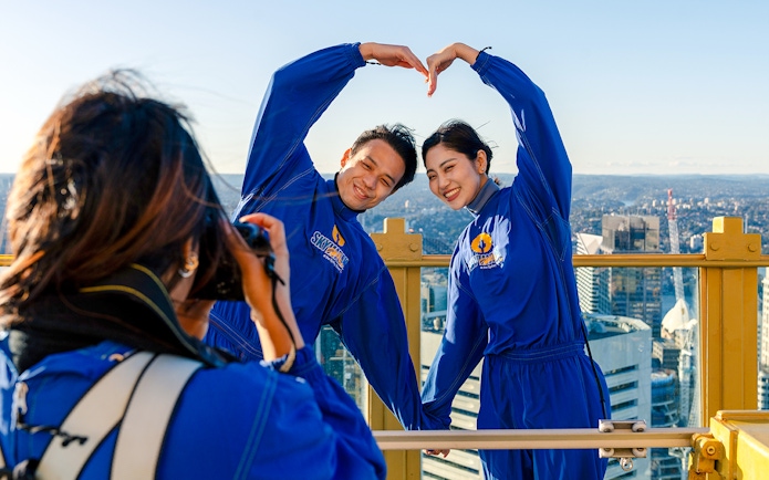 Couple posing on Sydney Tower Eye Skywalk with city view.