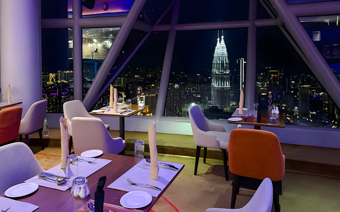Dining tables with a view of Kuala Lumpur skyline from Orbit Revolving Restaurant in KL Tower.