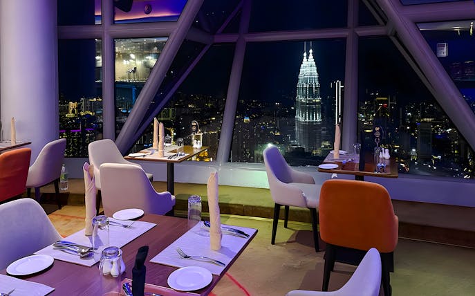 Dining tables with a view of Kuala Lumpur skyline from Orbit Revolving Restaurant in KL Tower.