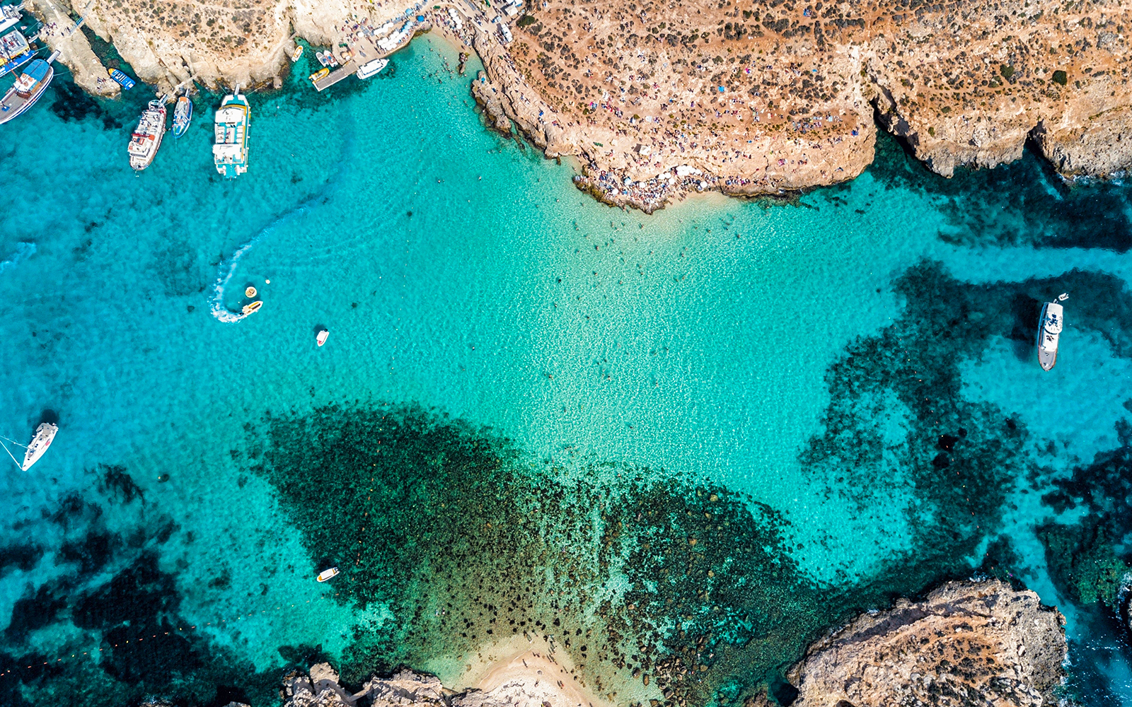 Aerial view of The Blue Lagoon in Malta with boats and clear turquoise water.