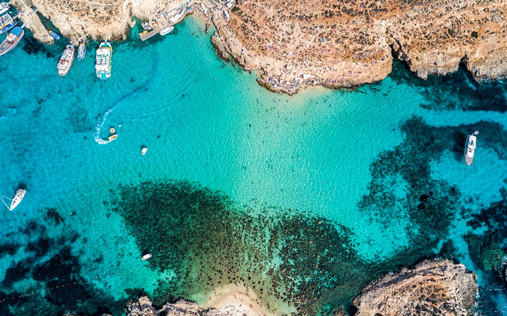 Aerial view of The Blue Lagoon in Malta with boats and clear turquoise water.