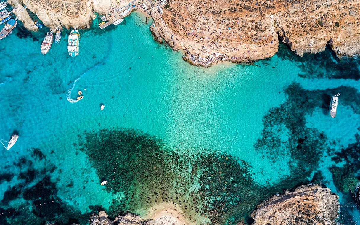 Aerial view of The Blue Lagoon in Malta with boats and clear turquoise water.