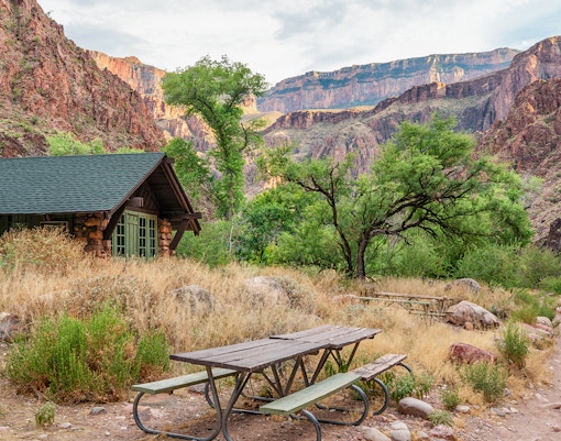 Phantom Ranch cabin and picnic area with Grand Canyon cliffs in the background.