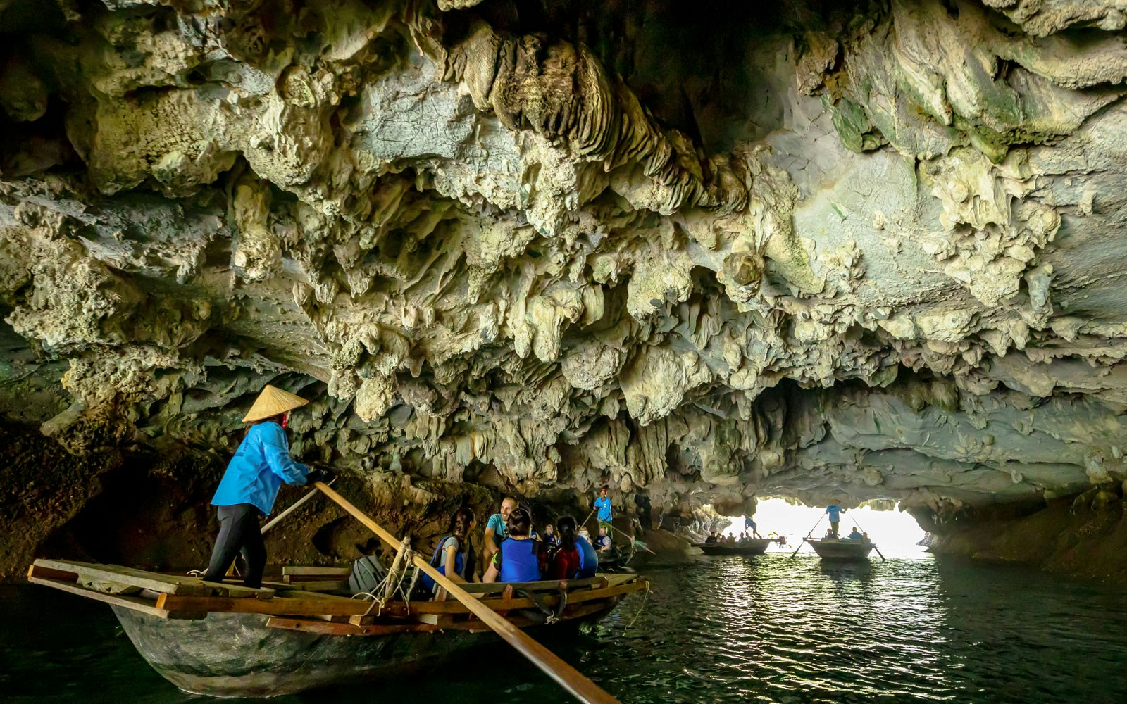 Tourists in a boat exploring Luon Cave, Halong Bay, Vietnam.