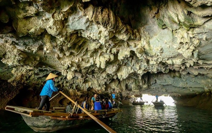 Tourists in a boat exploring Luon Cave, Halong Bay, Vietnam.