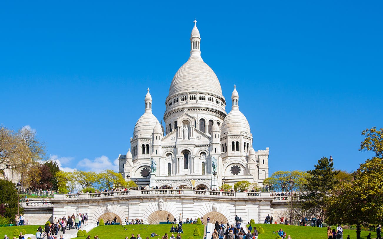 Montmartre Sacré-Cœur Cathedral with visitors on the lawn, Paris.