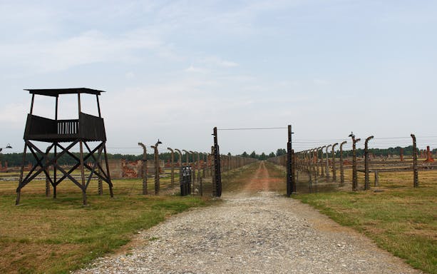 Auschwitz-Birkenau entrance with watchtower and barbed wire fence, Poland.