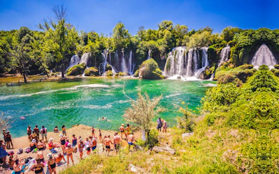 Visitors enjoying Kravica Waterfalls, lush greenery, and clear water near Dubrovnik.