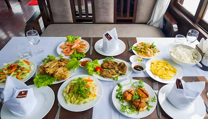 Dining table with Vietnamese dishes on Ha Long Phoenix Cruise, Halong Bay tour from Hanoi.