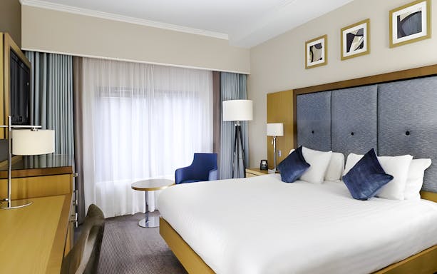 Hotel room with double bed, desk, and seating area included in Warner Bros Studio Tour package from London.