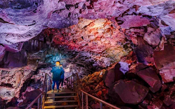 Guests exploring Raufarhólshellir Lava Tunnel with colorful rock formations.