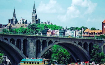 Boomerang yacht cruising on Potomac River with view of Georgetown University and Key Bridge, Washington DC.