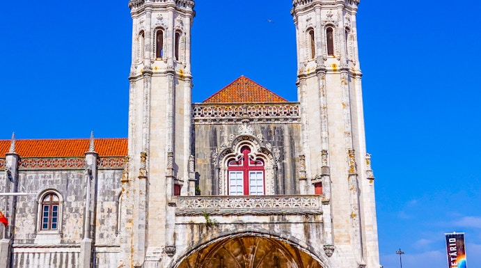 Facade of the Maritime Museum in Lisbon with twin spires and arched entrance.