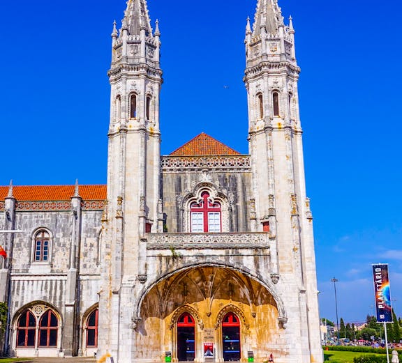 Facade of the Maritime Museum in Lisbon with twin spires and arched entrance.