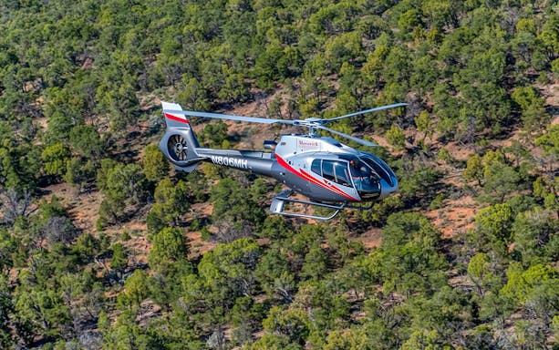 Helicopter flying over forested area on Maverick Aviation Grand Canyon Tour.
