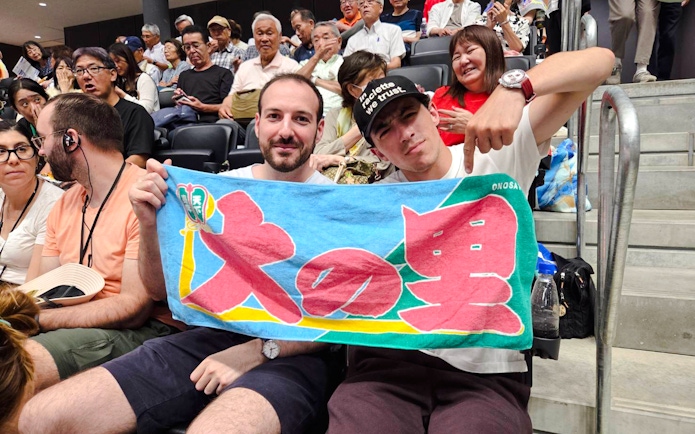Spectators holding a colorful banner at the Nagoya Grand Sumo Tournament.