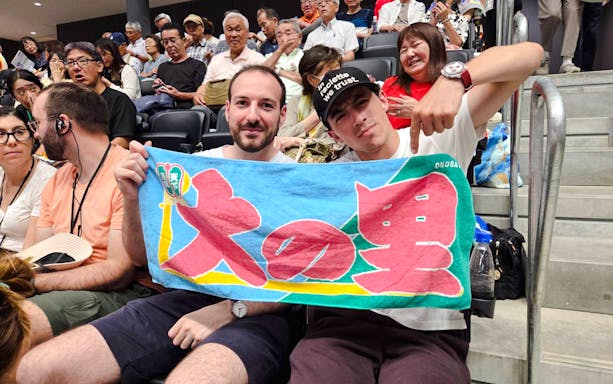 Spectators holding a colorful banner at the Nagoya Grand Sumo Tournament.