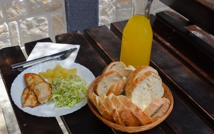 Mediterranean meal with grilled chicken, cabbage salad, bread, and juice on Blue Lagoon tour from Split.