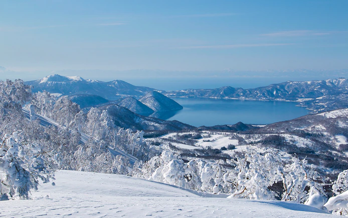 Snow-covered landscape with Lake Toya and surrounding mountains in Hokkaido, Japan.