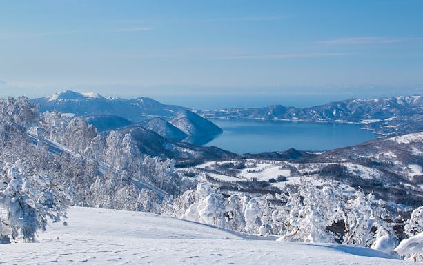 Snow-covered landscape with Lake Toya and surrounding mountains in Hokkaido, Japan.