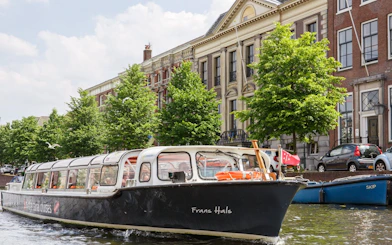 Canal boat cruising in Haarlem with historic buildings in the background.