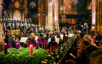 Orchestra performing inside St. Stephen's Cathedral, Vienna, with audience seated.