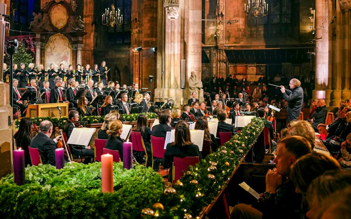 Orchestra performing inside St. Stephen's Cathedral, Vienna, with audience seated.