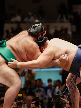 Sumo wrestlers grappling in a match at a tournament in Japan.
