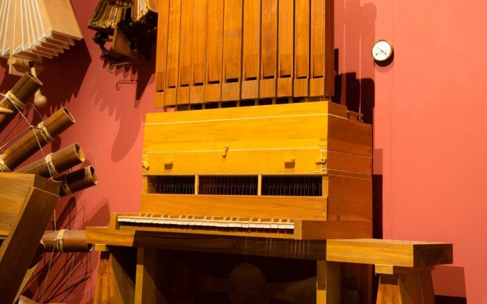 Continuous Organ exhibit at Leonardo3 Museum, featuring wooden pipes and keyboard.