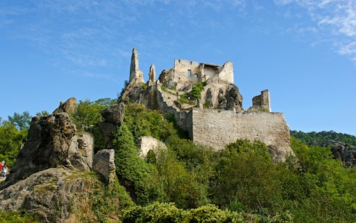 Dürnstein Castle ruins atop a rocky hill in Wachau Valley, surrounded by greenery.