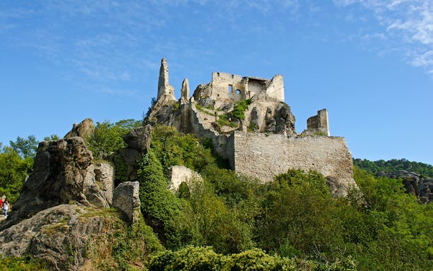 Dürnstein Castle ruins atop a rocky hill in Wachau Valley, surrounded by greenery.
