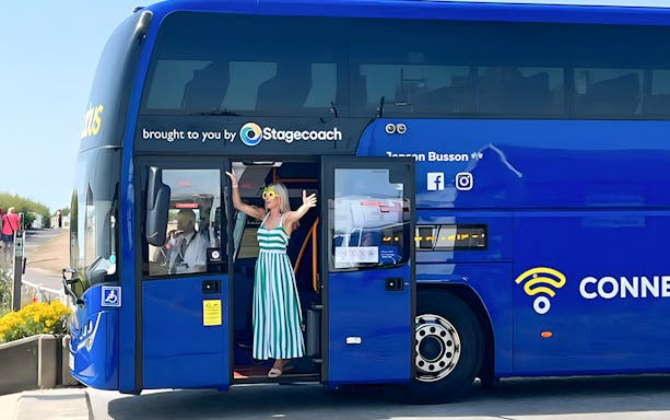 Woman enjoying a ride on a Megabus, standing at the open door.