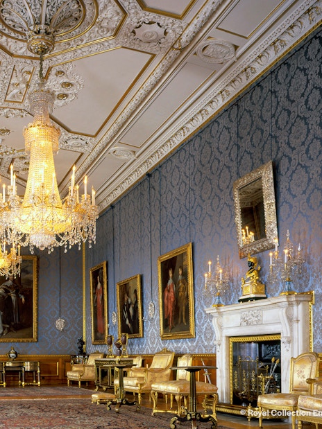 Windsor Castle interior with ornate chandeliers, blue damask walls, and classic paintings.