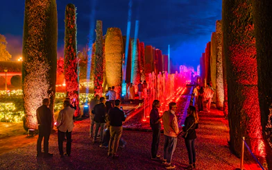 Alcazar of Cordoba garden illuminated at night with colorful lights and fountains.