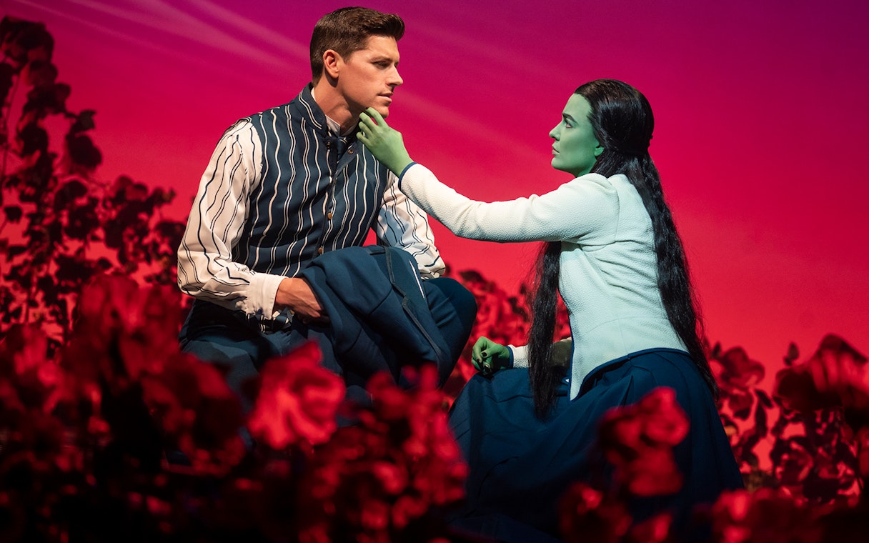 Characters from the musical Wicked in an emotional scene on stage.