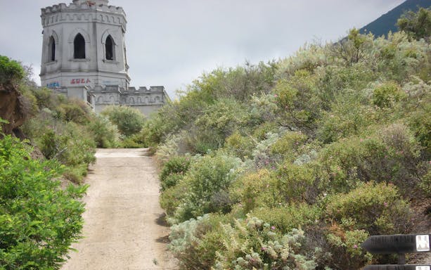 Pathway leading to a historic tower surrounded by greenery on Lipari Island.