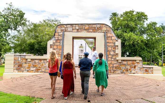 Group walking through historic stone archway on art tour.