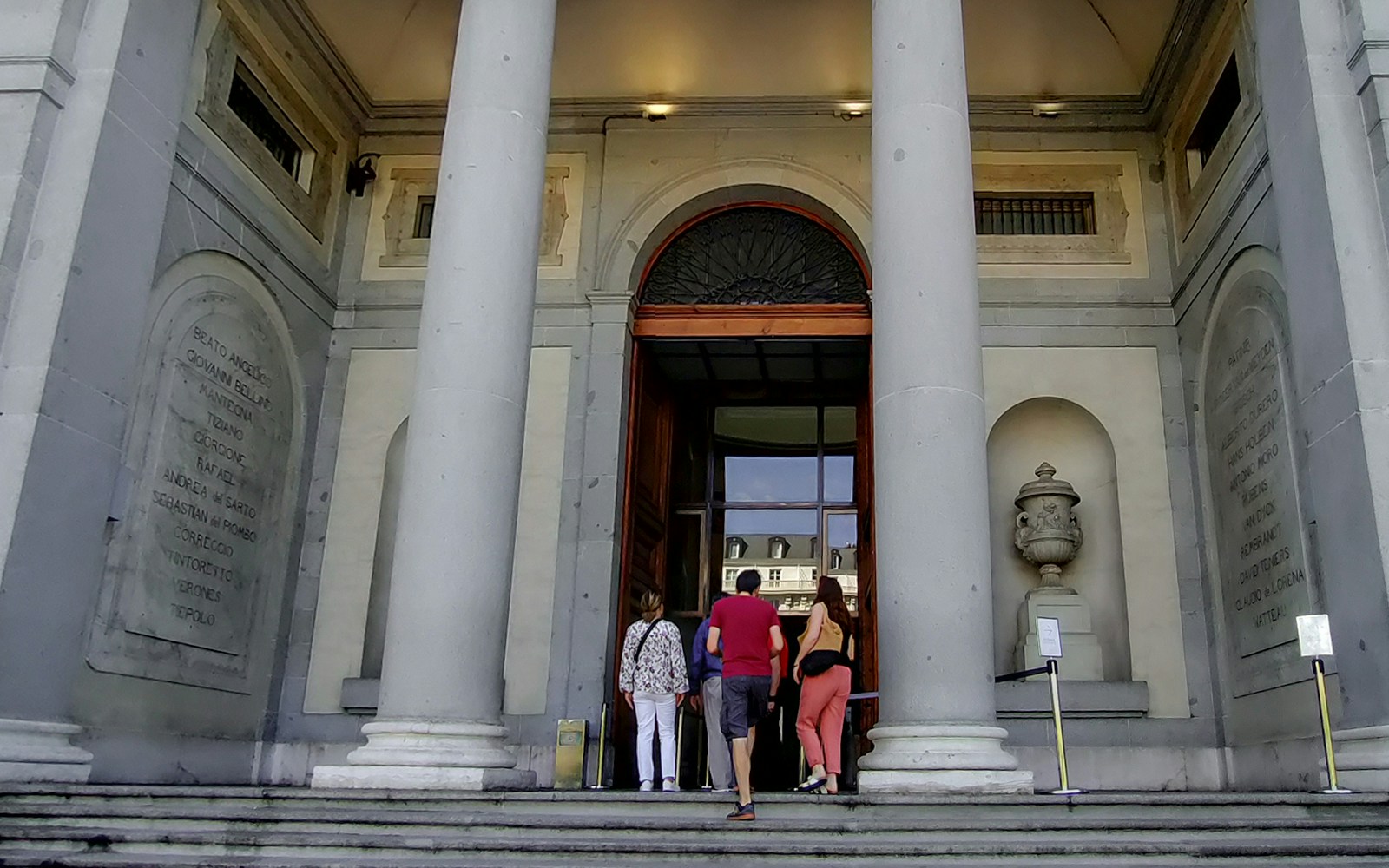 Visitors exploring art exhibits inside the Prado Museum, Madrid, during a guided tour.