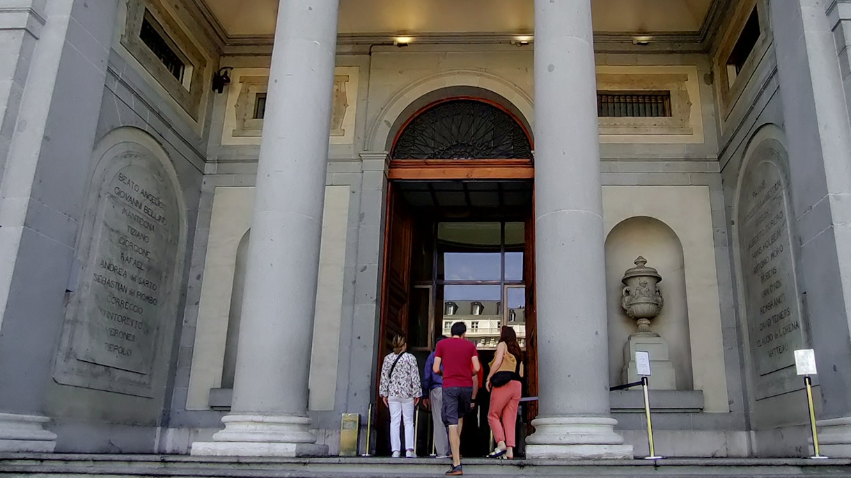 Visitors exploring art exhibits inside the Prado Museum, Madrid, during a guided tour.
