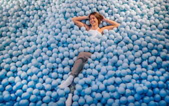 Person relaxing in a blue ball pit at Ikono Madrid.