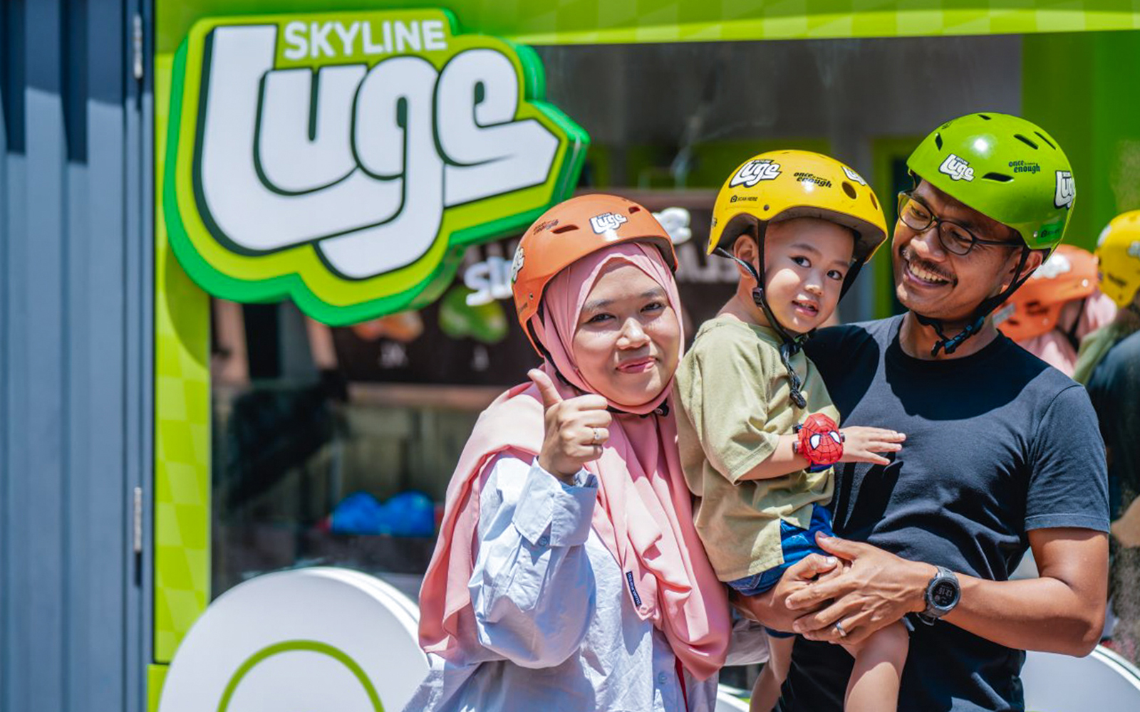 Family at Skyline Luge Kuala Lumpur, wearing helmets and smiling.