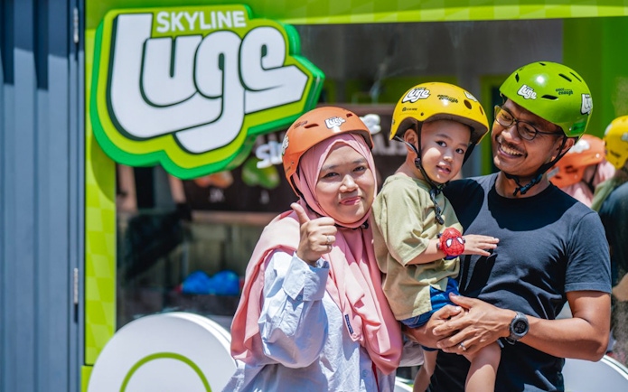 Family at Skyline Luge Kuala Lumpur, wearing helmets and smiling.