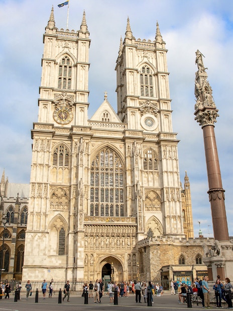 People gathered outside Westminster Abbey, London, admiring its Gothic architecture.