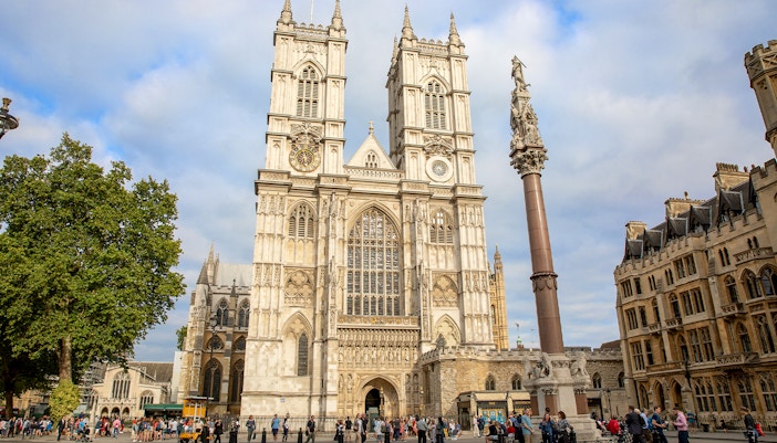 People gathered outside Westminster Abbey, London, admiring its Gothic architecture.