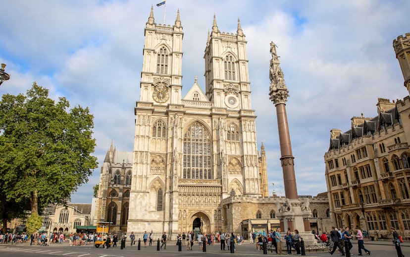 People gathered outside Westminster Abbey, London, admiring its Gothic architecture.